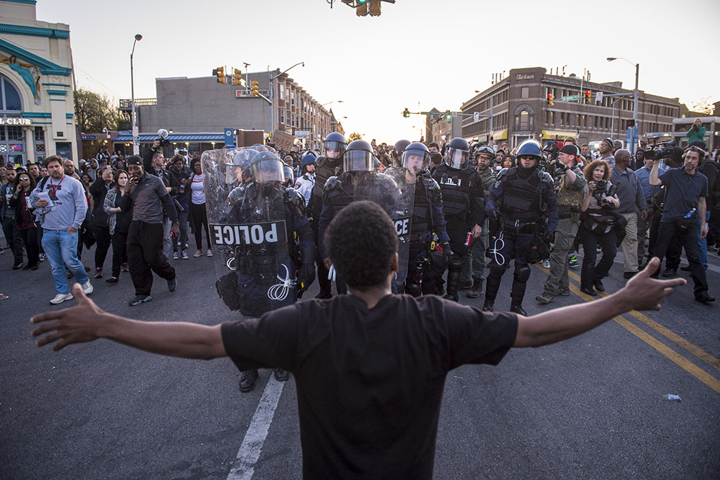 BALTIMORE, MD - APRIL 28: A man stops and yells at officers as they make their way through the crowd to help a person who needed medical attention near the intersection of West North Avenue and Pennsylvania Avenue as protestors walk for Freddie Gray on West North Avenue and protest around the city in Baltimore, MD on Tuesday April 28, 2015. Gray died from spinal injuries about a week after he was arrested and transported in a police van. (Photo by Jabin Botsford/The Washington Post)